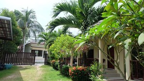 A residential property with a front yard, a wooden fence, and a house with a porch. - Ron's Bungalow (Choeng Thale)