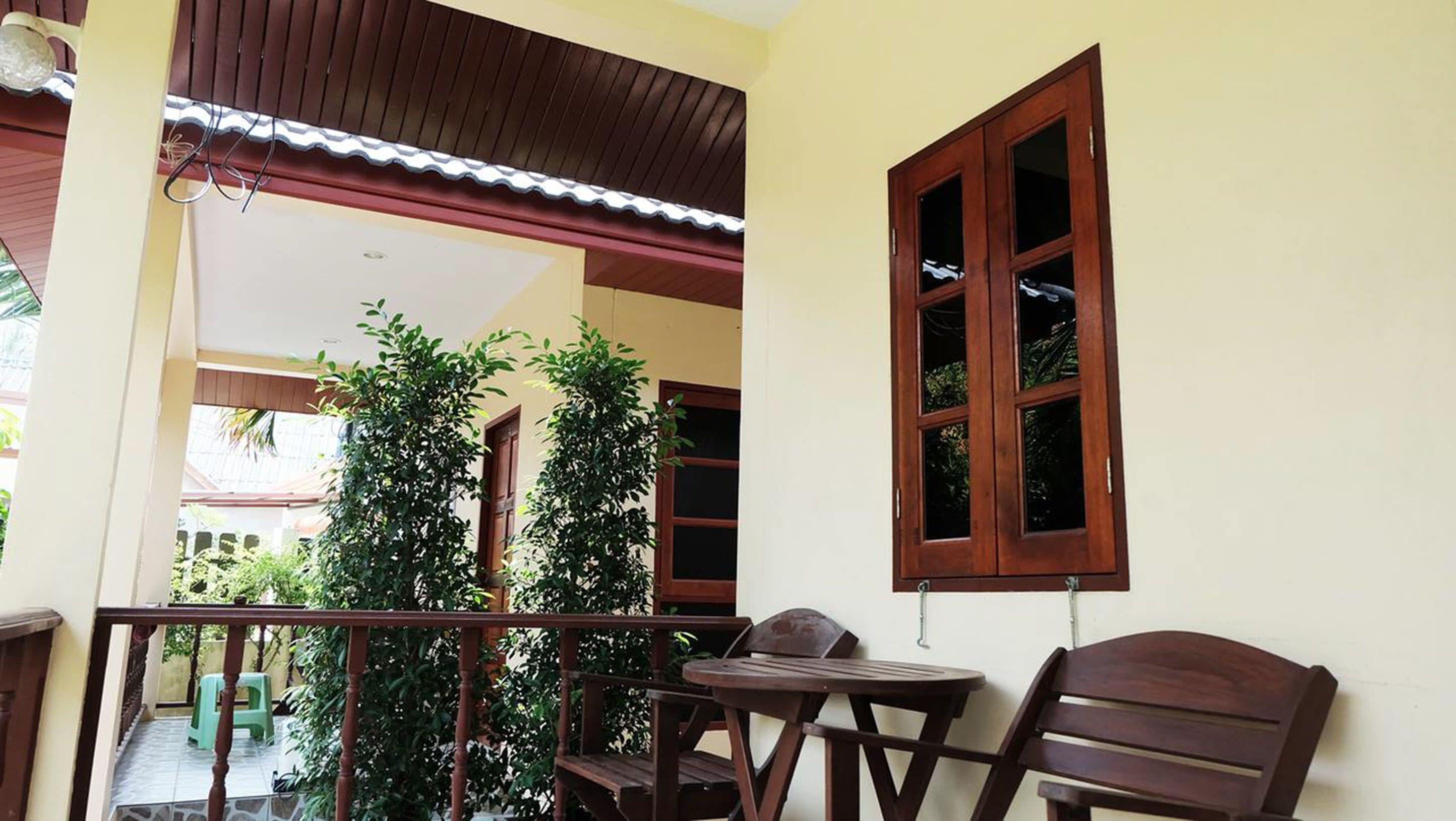 A balcony with wooden furniture, a window, and potted plants.