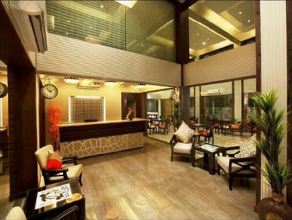 A lobby with a reception desk, seating area, and large windows. - Turtle Beach Resort - Morjim (Morjim)