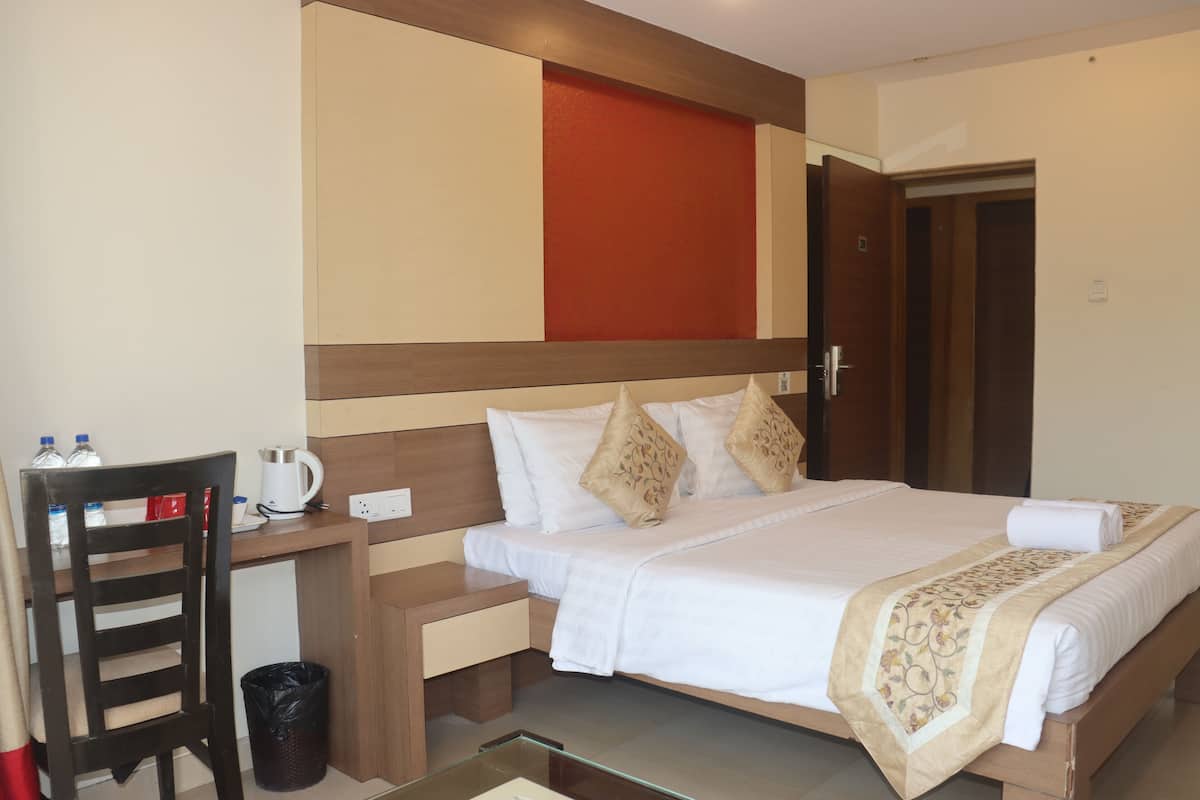A hotel room with a bed, bedside table, chair, and a desk with a chair.