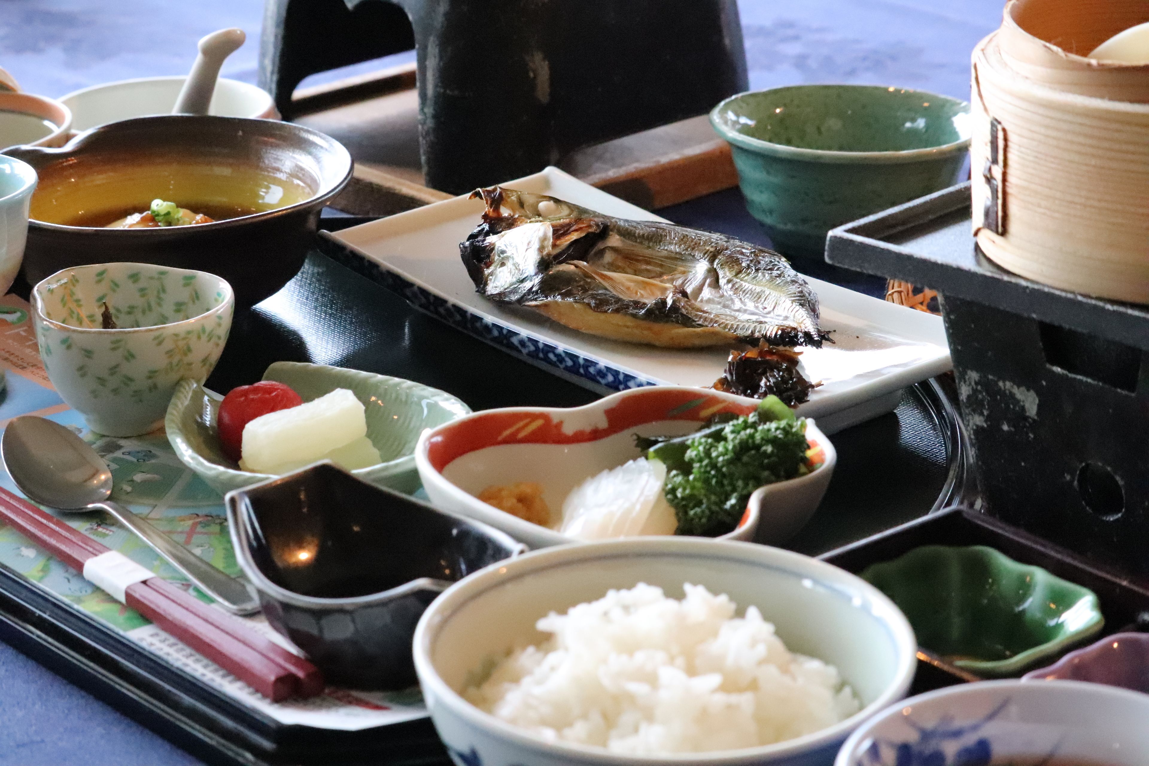 Eine traditionelle japanische Mahlzeit mit verschiedenen Gerichten, darunter Reis, Fisch und Gemüse.