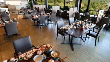 Un comedor amplio con varias mesas dispuestas para comidas, grandes ventanales que ofrecen vistas al exterior y un diseño interior moderno.