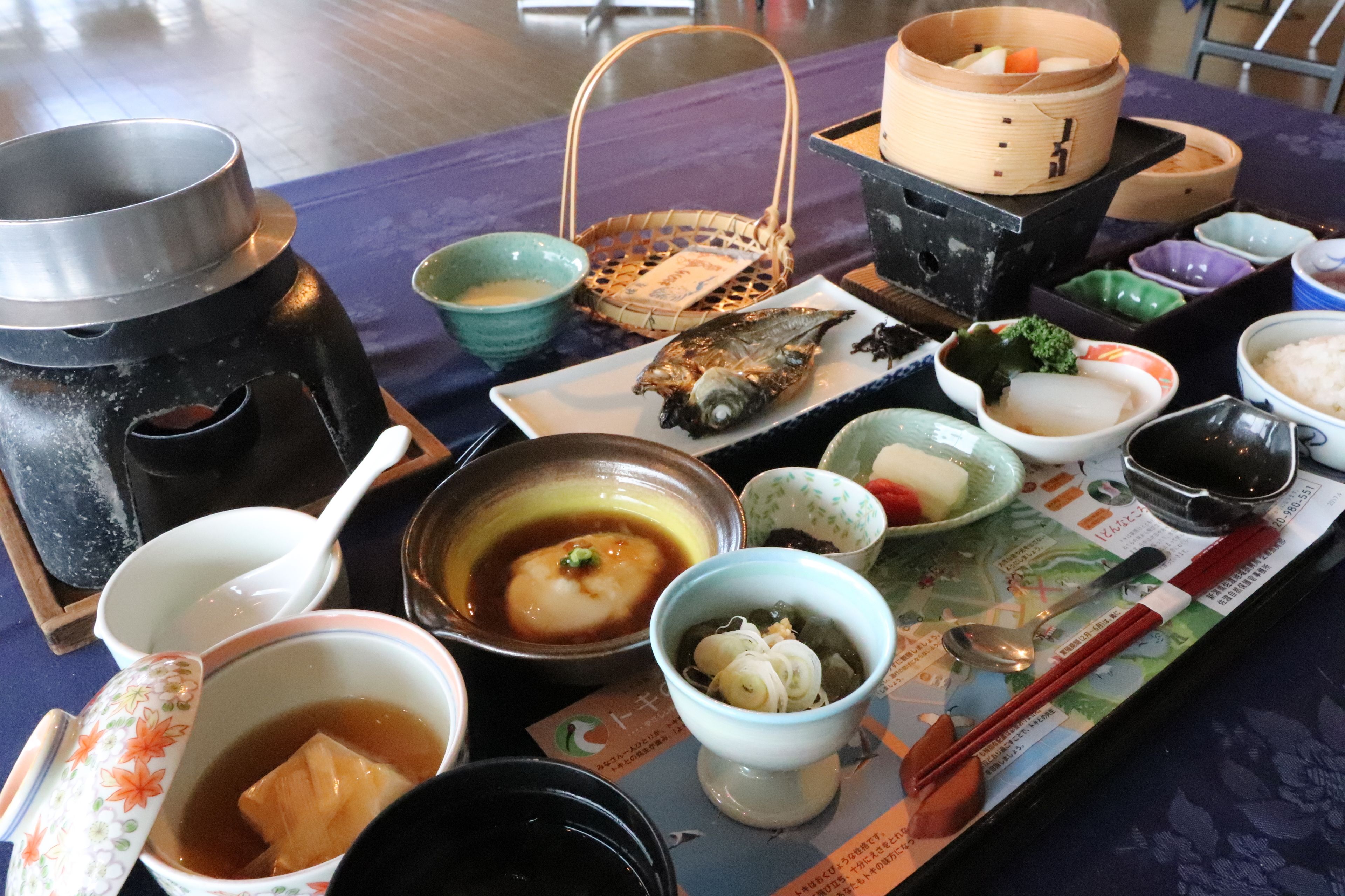 A table set with various dishes, including a fish, bowls of soup, and a teapot.