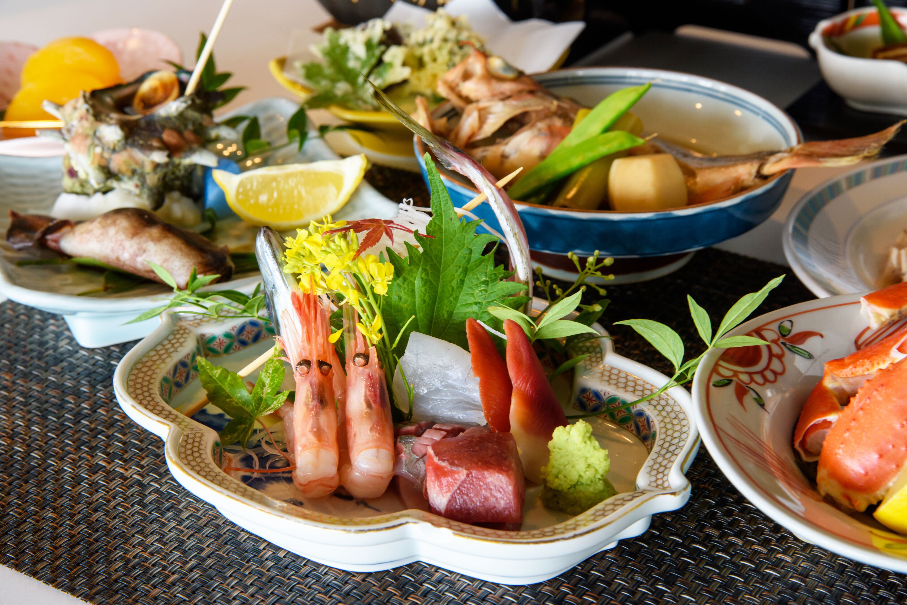 A variety of seafood dishes on a table with a woven tablecloth.