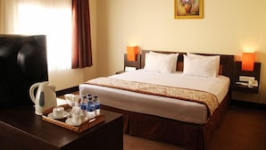 Habitación de hotel con cama, dos lámparas de noche, una mesita de centro con una bandeja de desayuno y un cuadro en la pared.