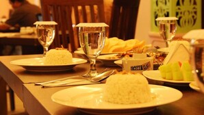 Una mesa de comedor con platos de arroz, un vaso y una caja de salsas.