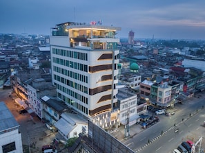 Un hotel de varios pisos con diseño moderno, que cuenta con balcones y una terraza en la azotea.