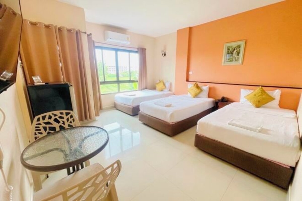 Habitación de hotel con dos camas, una mesa de vidrio, una silla y un televisor.