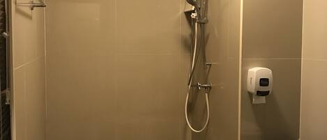 A small, enclosed shower area with a toilet and a hand dryer.