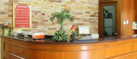 A reception desk with a wooden finish, a potted plant, and a framed sign with text.