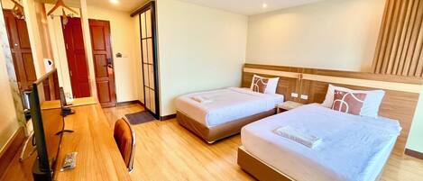 Habitación de hotel con dos camas, un escritorio con computadora, un espejo y un armario.