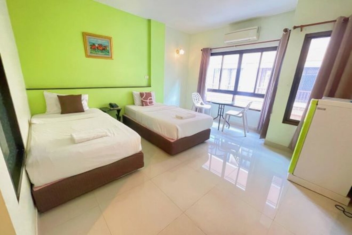 Habitación de hotel con dos camas, una mesa de comedor, una silla y un refrigerador.