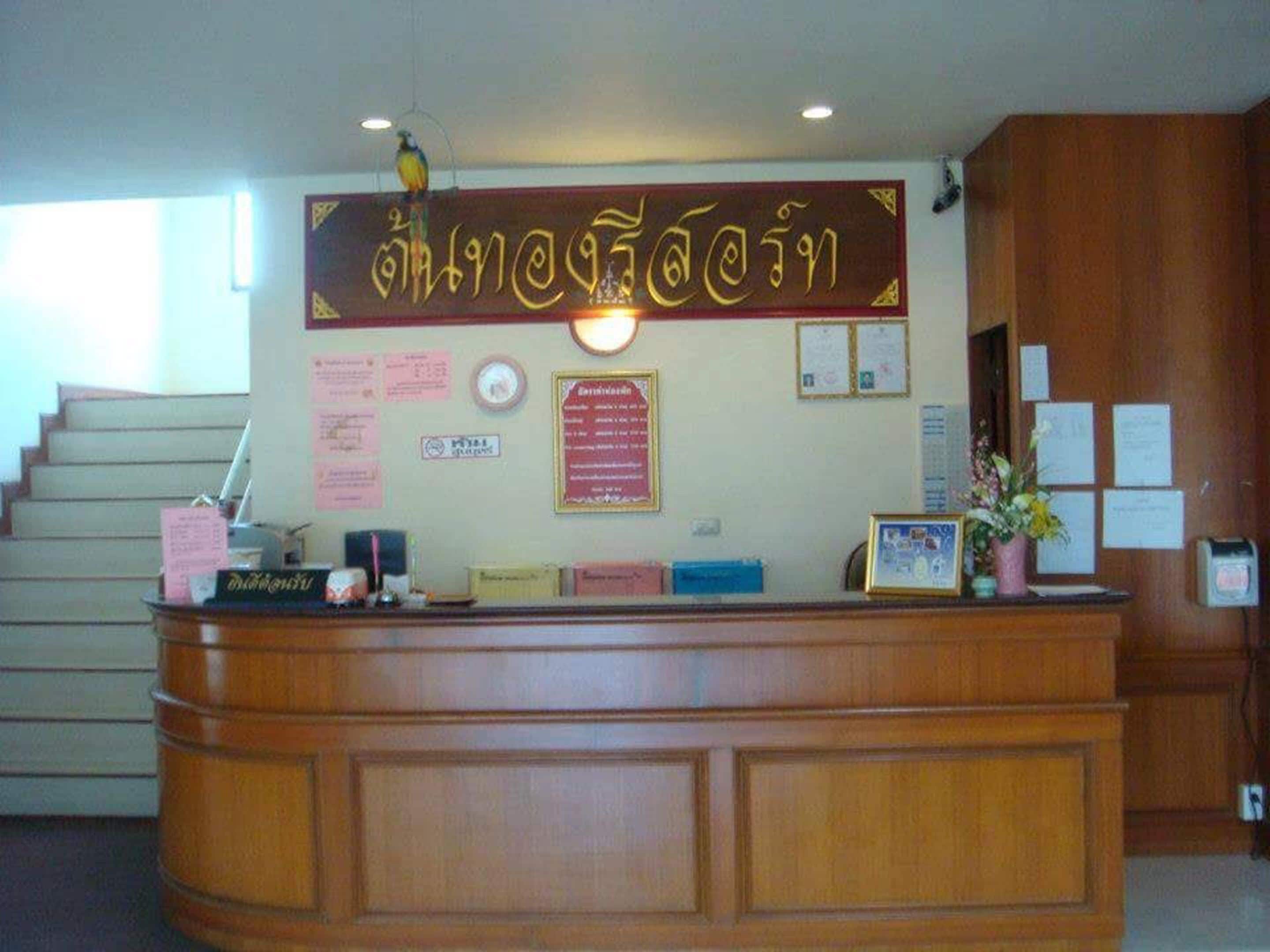 A reception desk with a wooden finish, a wall-mounted sign with text, and various notices and certificates.
