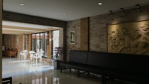 Un hall moderno con un banco, sillas blancas, un separador de vidrio y una pared de ladrillo con una escultura de caballo.