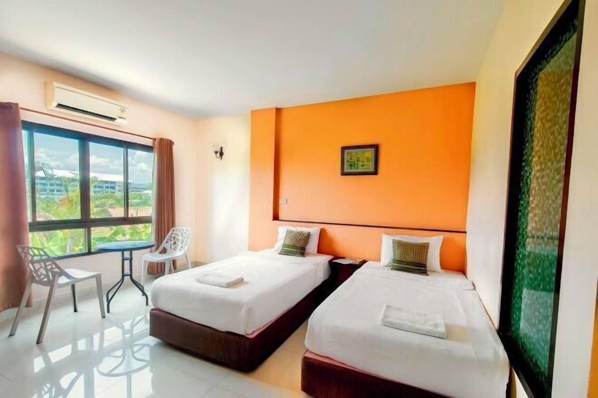 Une chambre d’hôtel avec deux lits, une fenêtre donnant sur un paysage agréable, une table et des chaises.