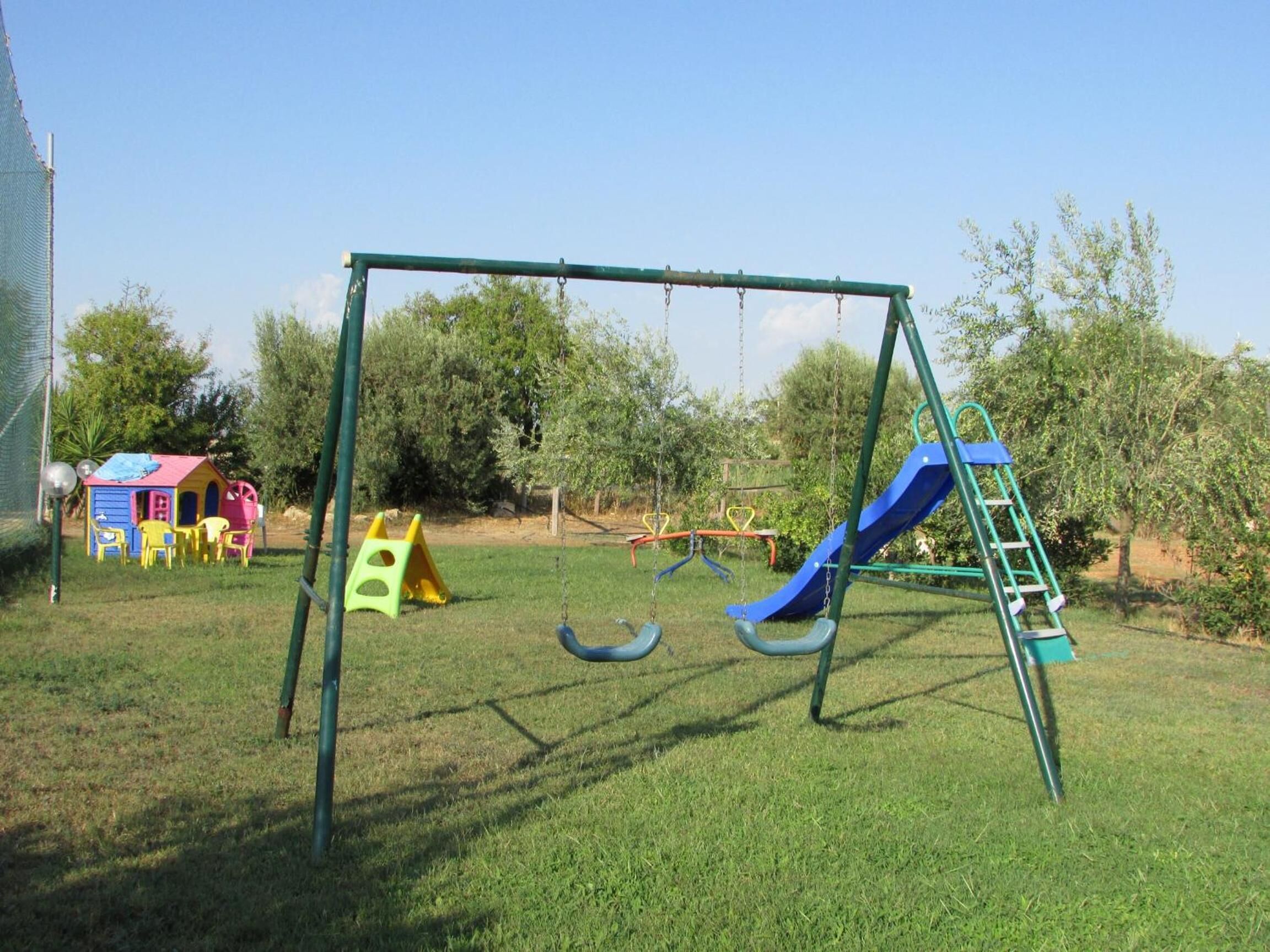 Un'area giochi con altalene, uno scivolo e una piccola casetta.