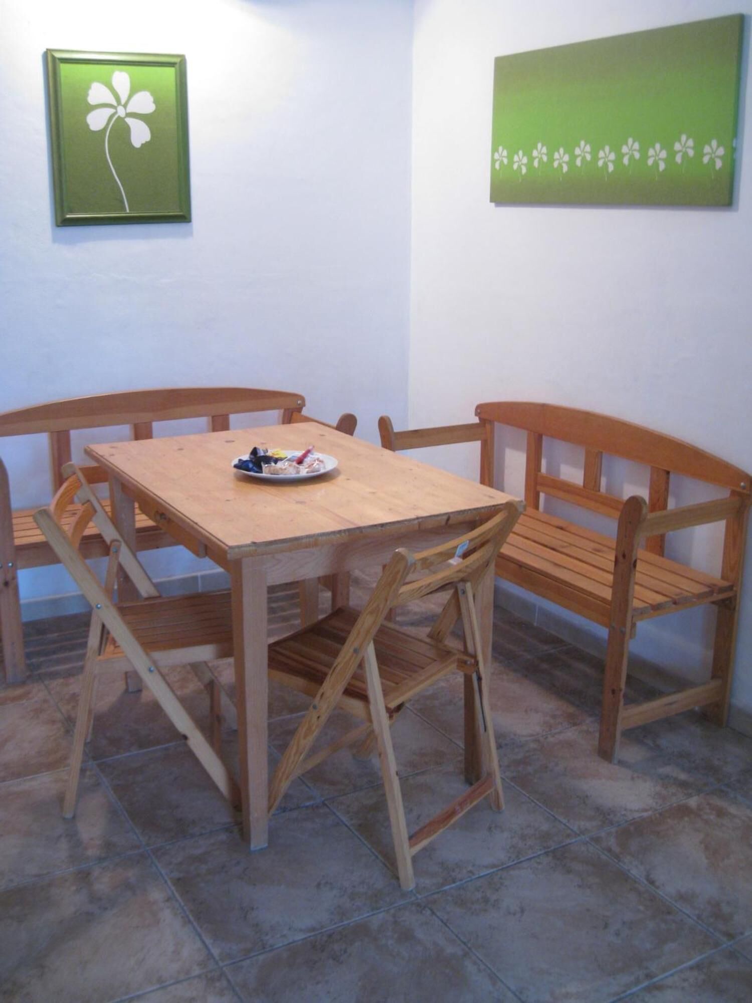 Una mesa de madera con cuatro sillas, un plato de comida y dos cuadros en la pared.