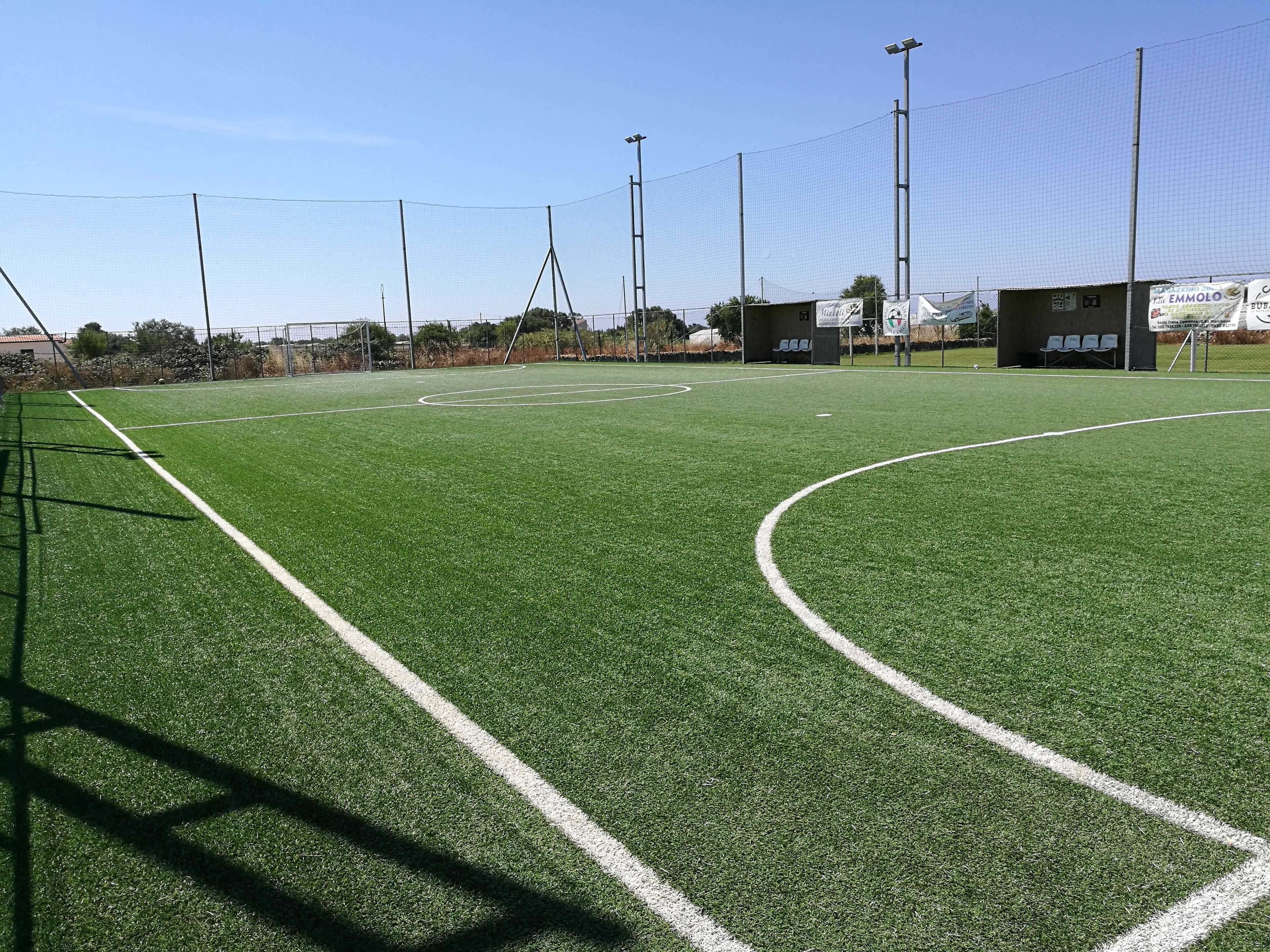 Un terrain de sport avec des poteaux de but, une clôture et un petit bâtiment doté de sièges.
