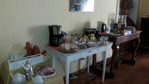 Una mesa con una variedad de alimentos y bebidas para un desayuno tipo buffet, una cafetera y una tetera.