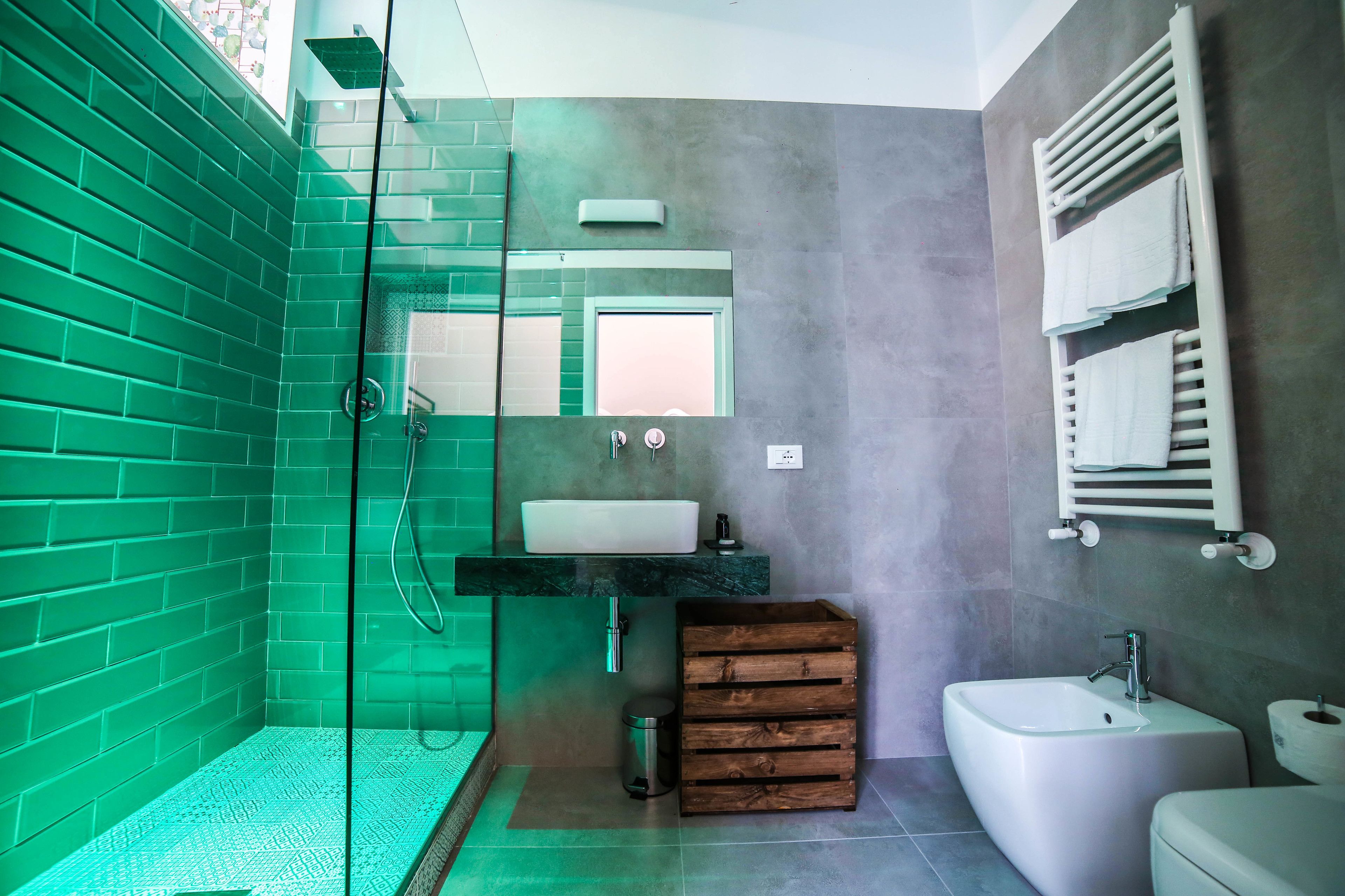 Un baño moderno con cabina de ducha de vidrio, lavamanos con encimera de mármol y mueble de tocador de madera.