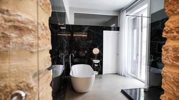Un baño moderno con una bañera independiente, una cabina de ducha con paredes de vidrio y suelo de mármol.