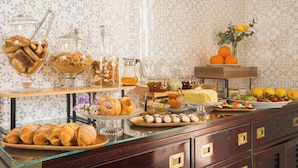 A buffet with various pastries, fruits, and a vase of flowers. - Family Affair (Palermo)