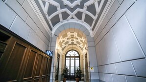 A hallway with a checkered floor, a large arched doorway, and two potted plants. - Family Affair (Palermo)