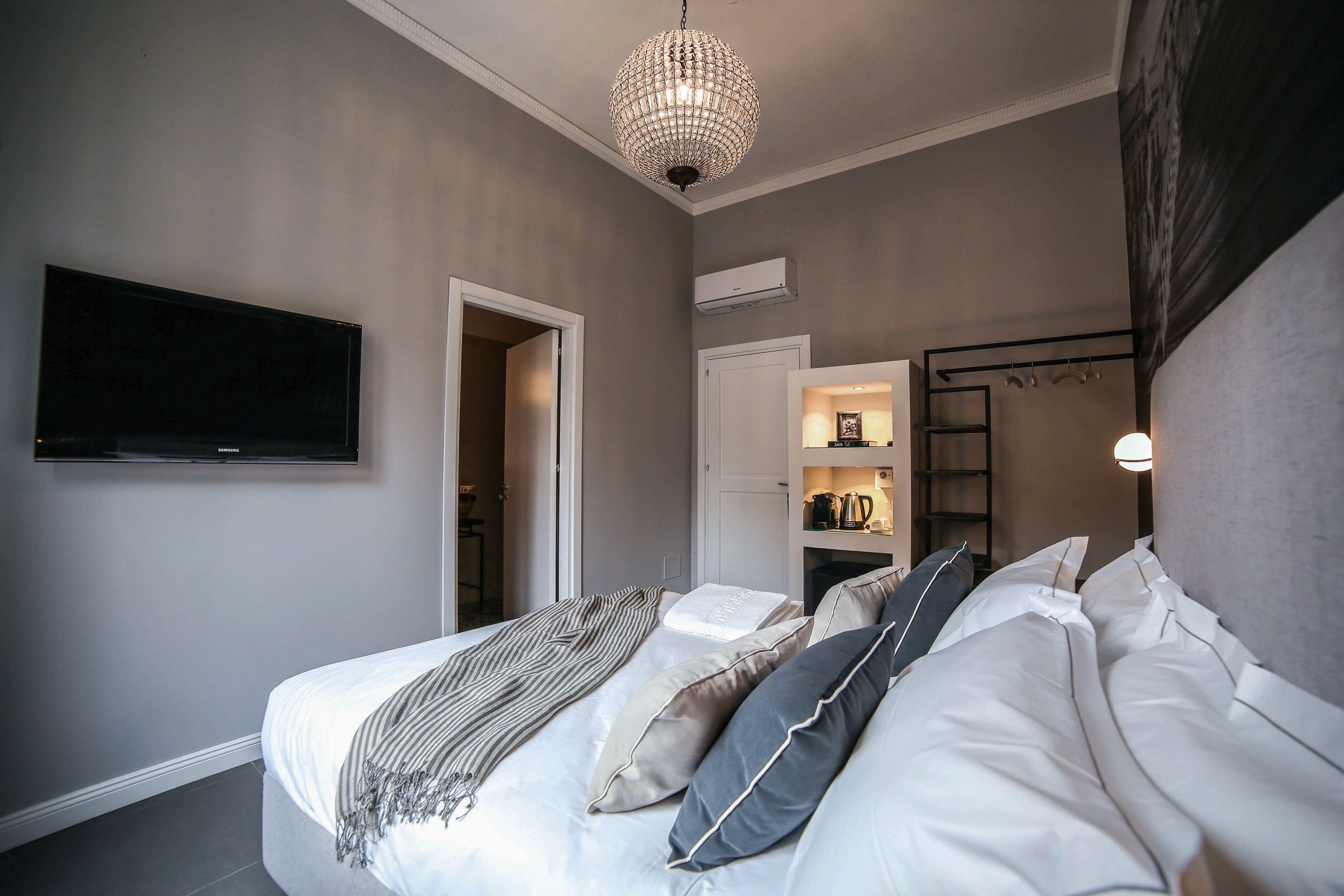 Une chambre à coucher comprenant un lit, une télévision, un lustre et une porte donnant accès à une salle de bain.