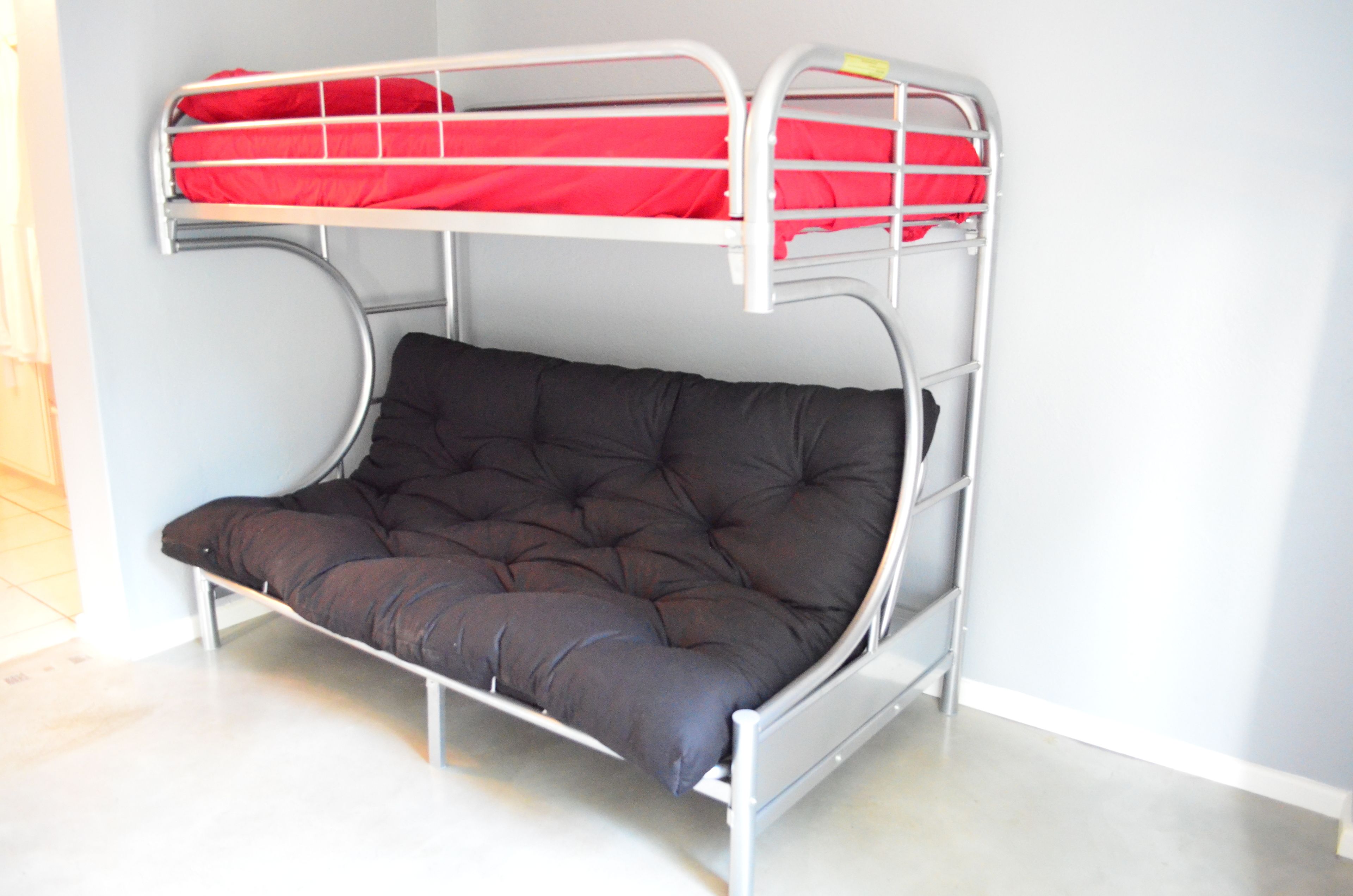 Un lit superposé avec un matelas et du linge de lit rouge.