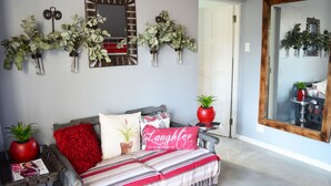 Quarto com uma cama, um travesseiro vermelho, manta listrada e duas plantas em vasos.