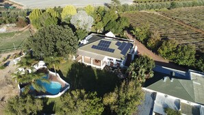 Uma casa com piscina, cercada por árvores e painéis solares no telhado.