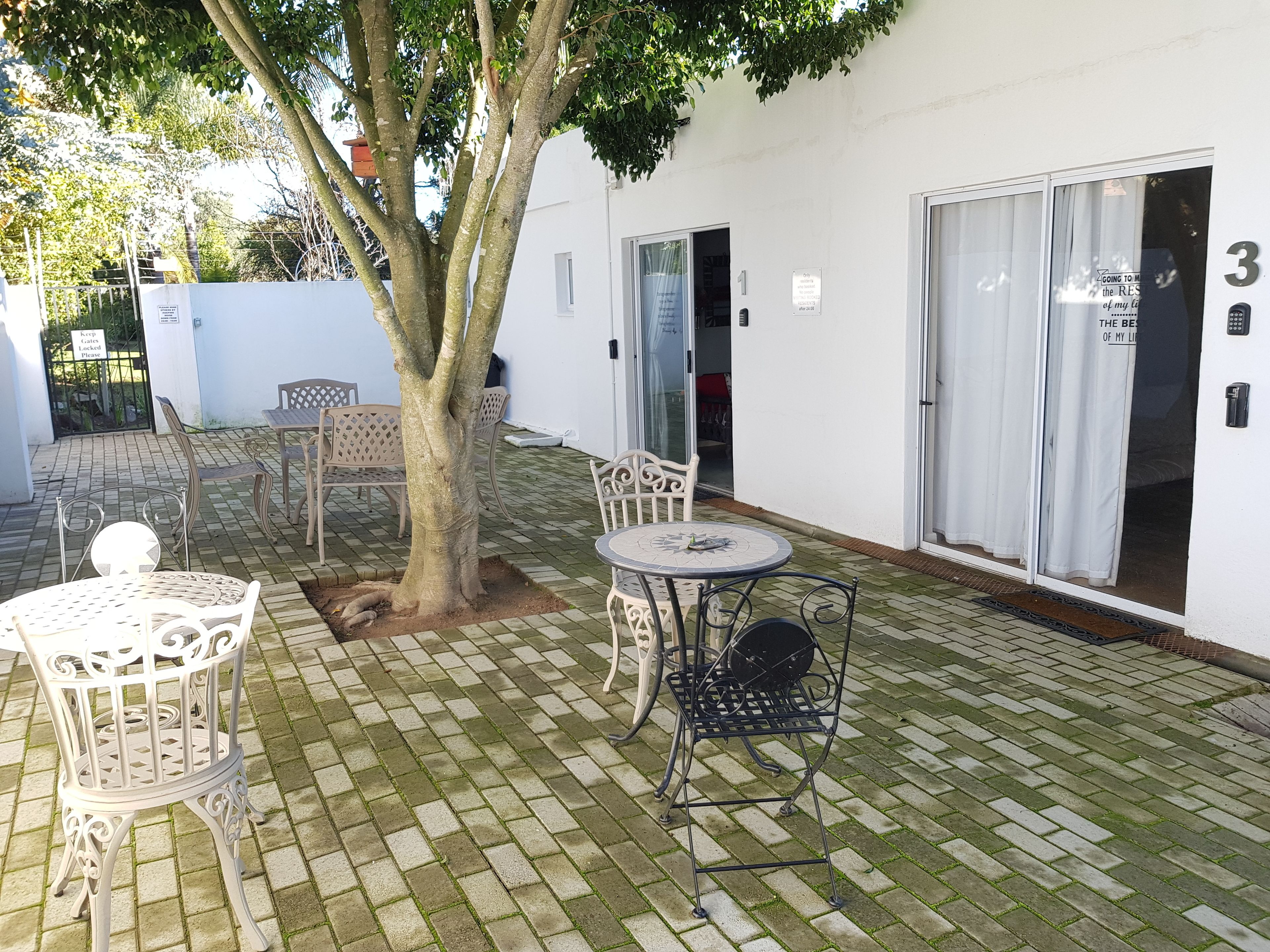 A courtyard with a tree, outdoor furniture, and a building entrance.