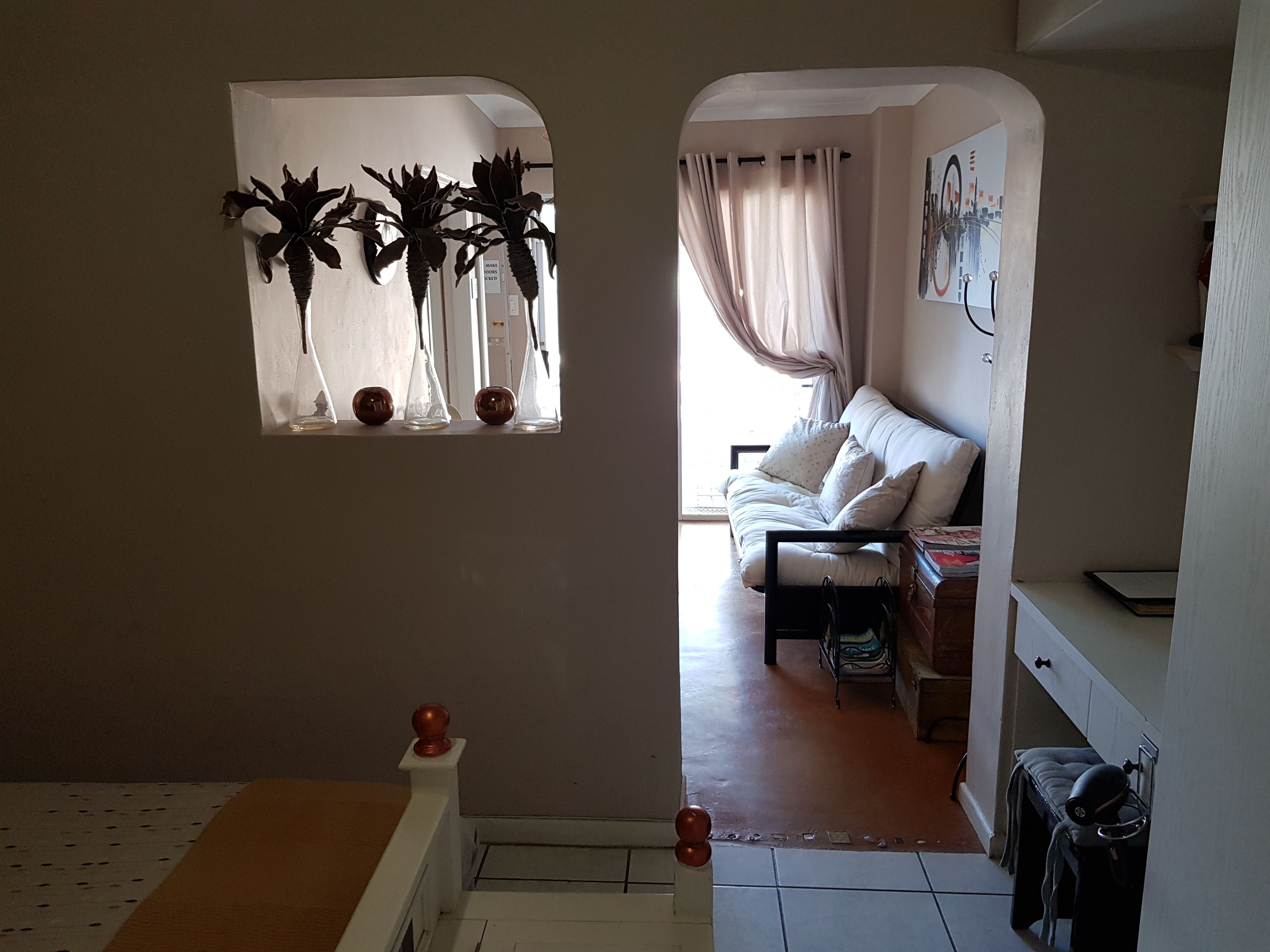 Una sala de estar con un sofá, una mesita y una ventana con plantas decorativas.