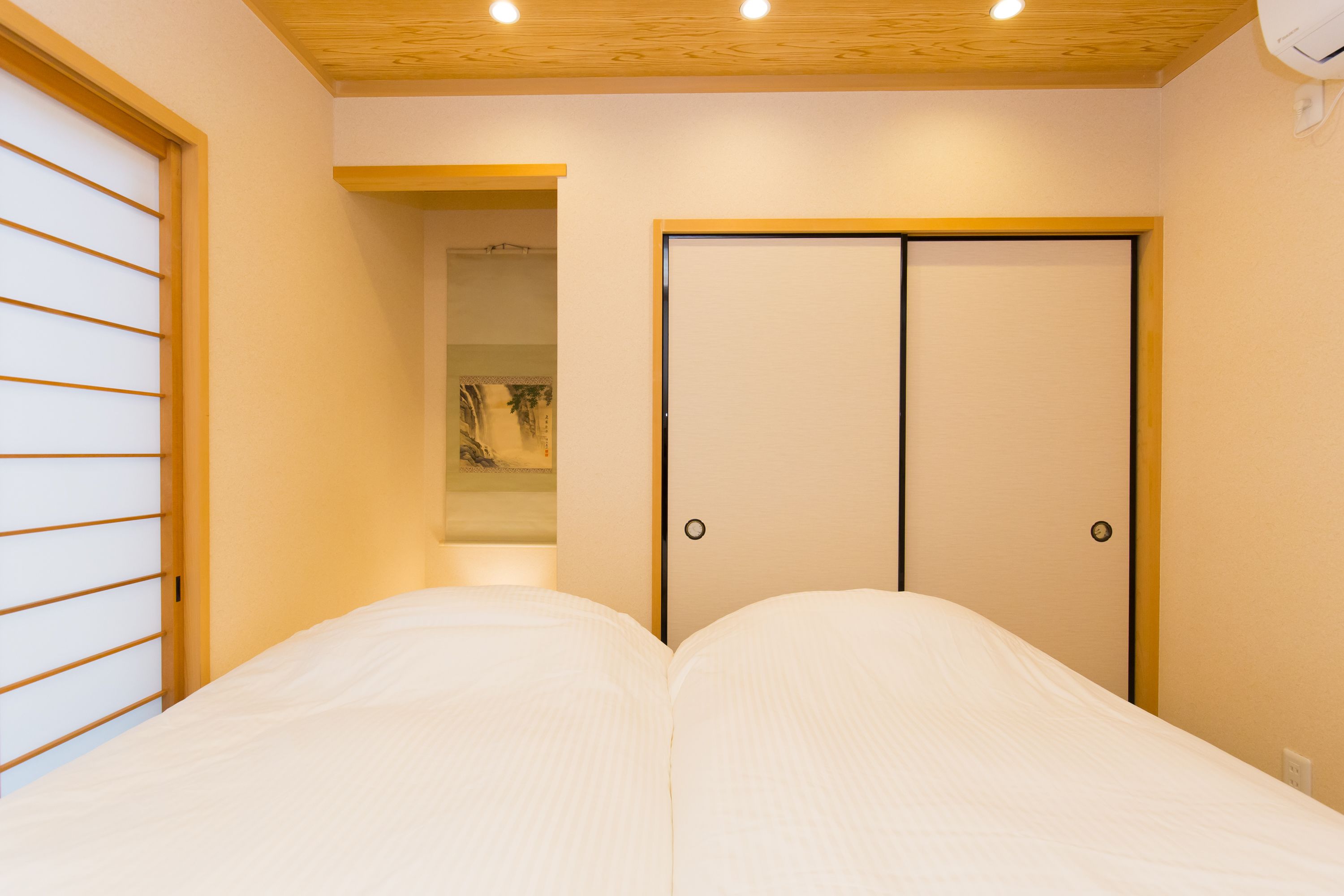 A hotel room with a bed, a wardrobe, and a wooden ceiling.