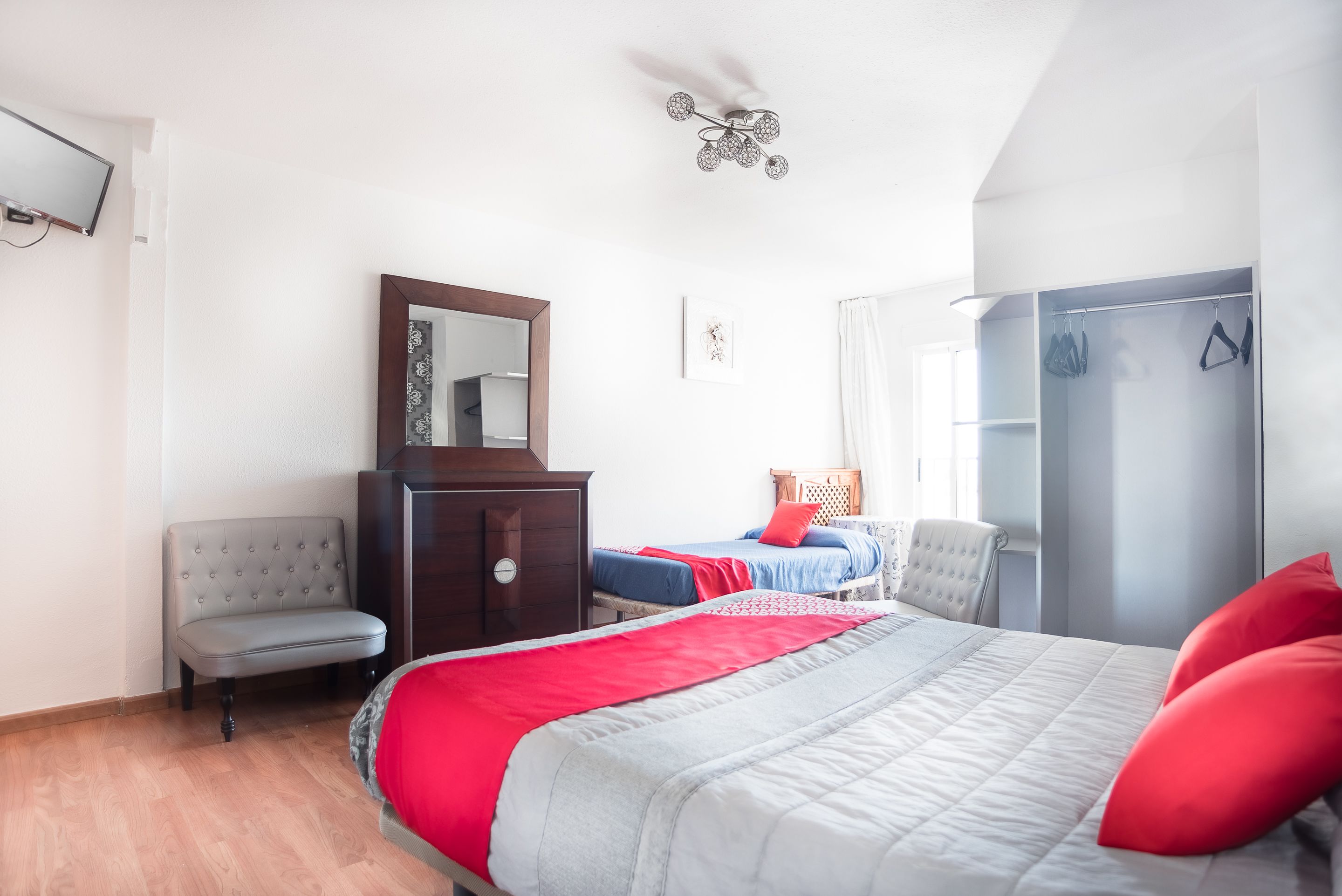A bedroom with a bed, a dresser, a chair, a wardrobe, and a ceiling fan.
