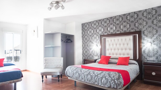 A bedroom with a large bed, a wardrobe, a chair, and a ceiling fan. - Hostal del Campo (Arévalo)