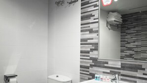 A modern bathroom with a toilet, sink, and a mirror with a patterned backsplash. - Hostal del Campo (Arévalo)