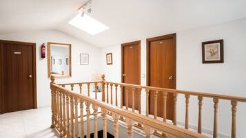 A hallway with wooden doors, a wooden railing, and a ceiling light fixture.