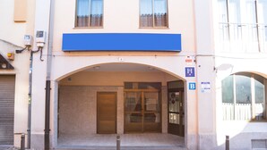 A building entrance with a blue awning, a glass door, and a sign with a letter 'B'. - Hostal del Campo (Arévalo)