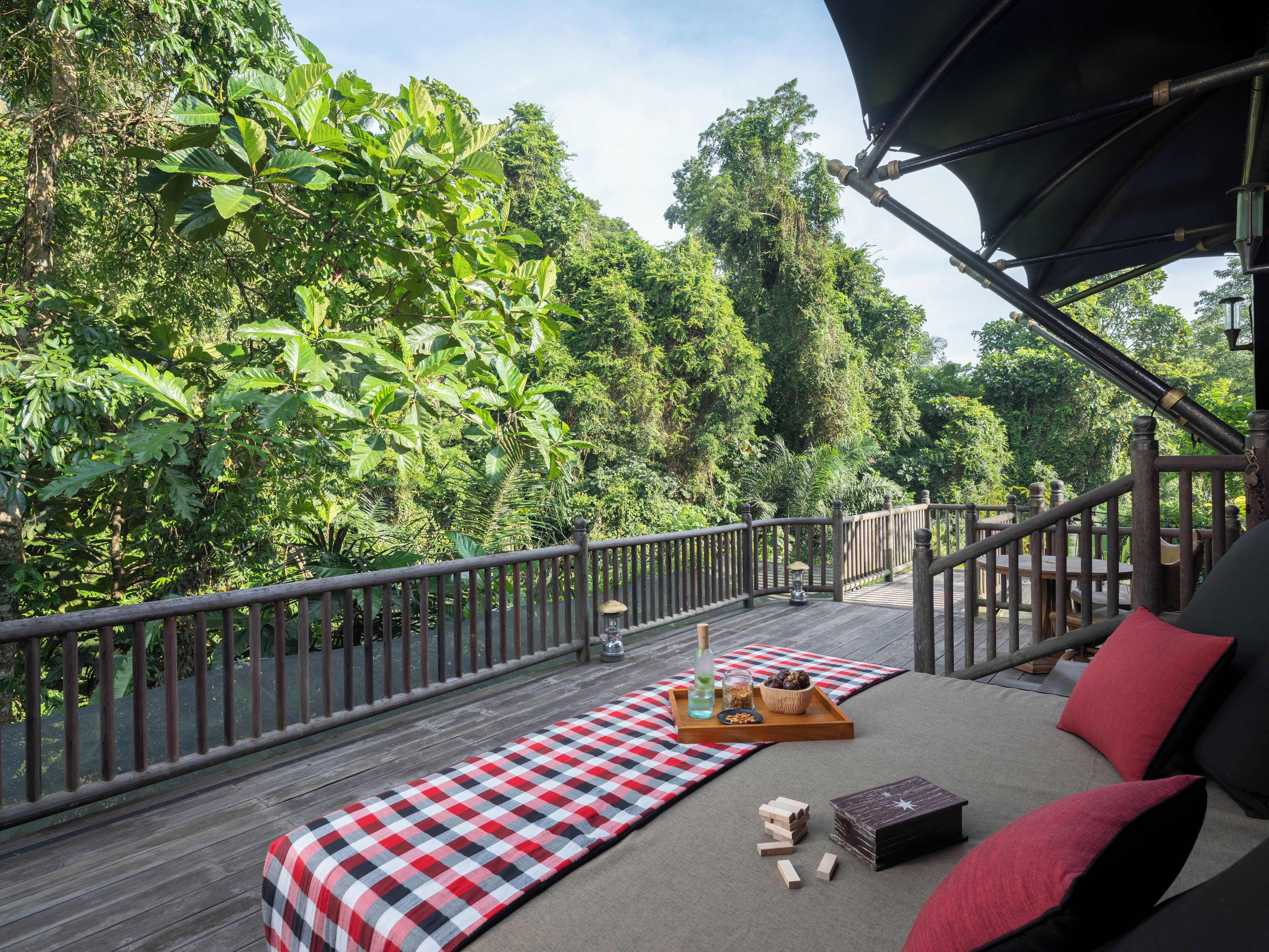 A wooden deck with a checkered mat, a tray with snacks, and a bottle.