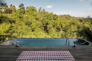 Relax by the serene pool surrounded by lush greenery and palm trees.