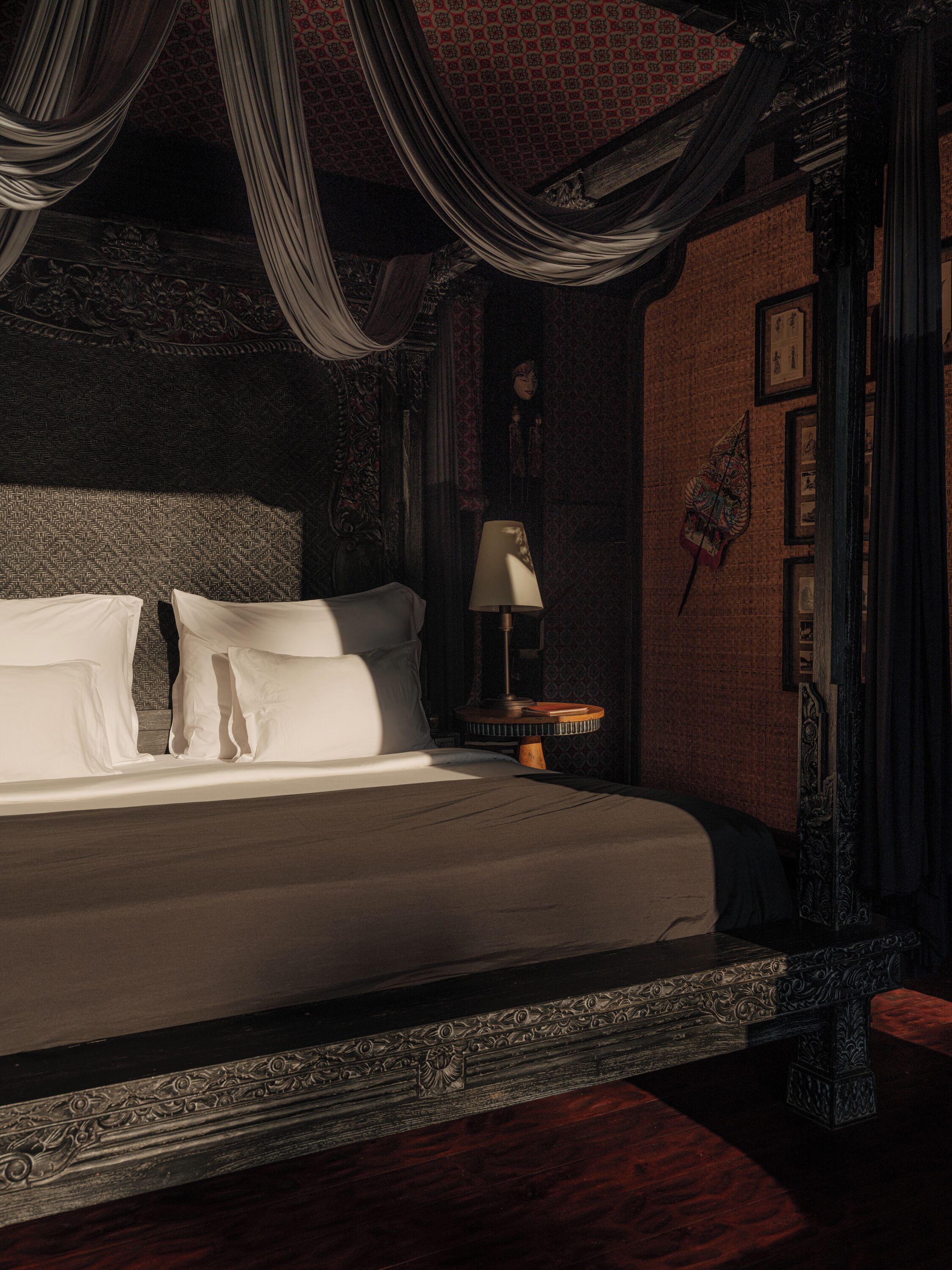 A bedroom with a large bed, a nightstand, and a lamp.