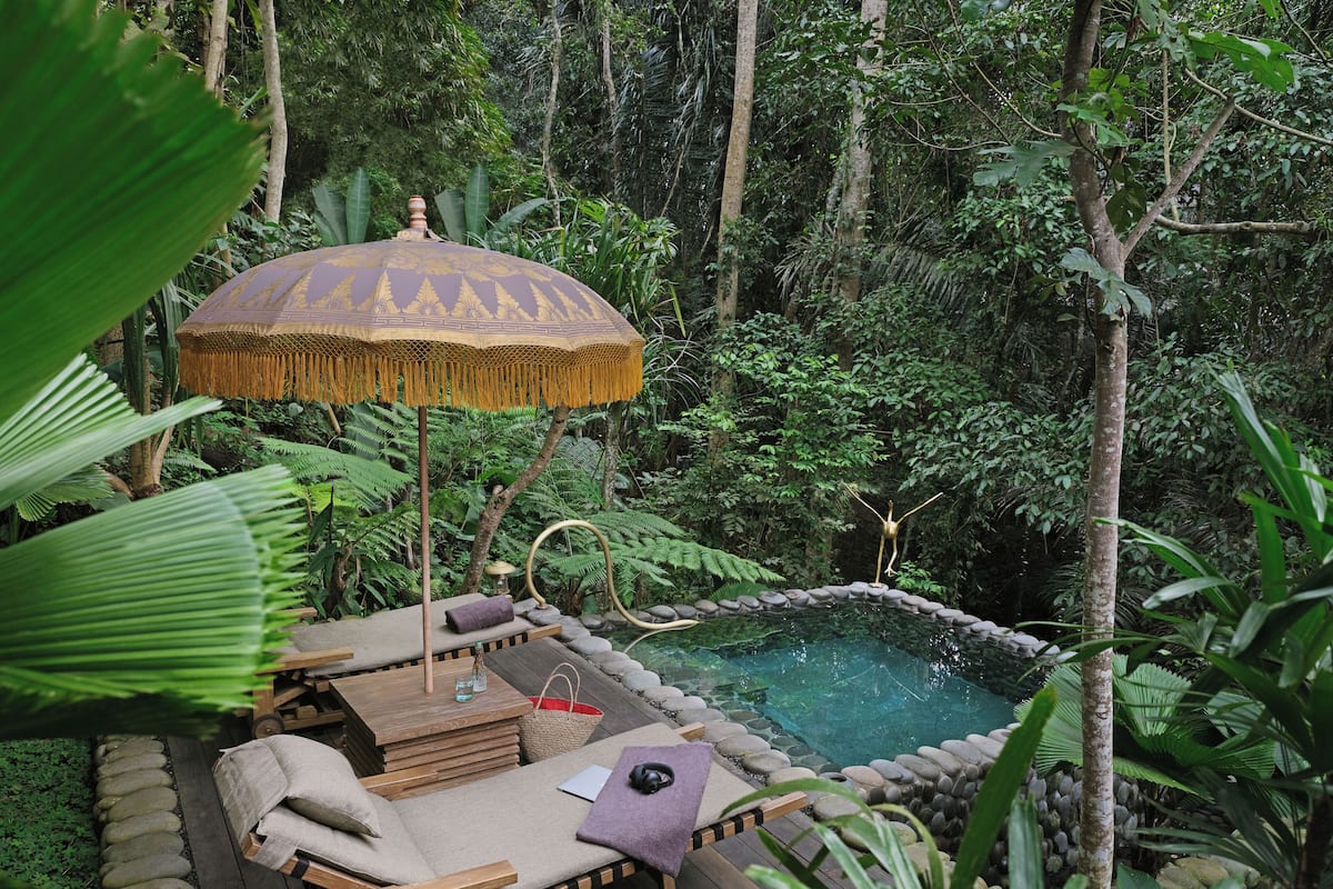 Eine Holzterrasse mit Liegestühlen, einem kleinen Pool und einem Zierteil-Sonnenschirm.