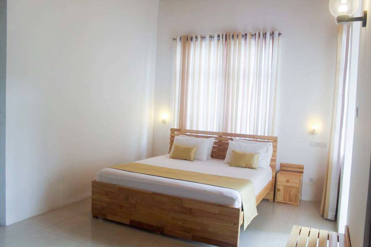 Een slaapkamer met een houten bed, witte beddengoed en een nachtkastje.
