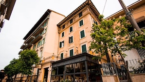 A multi-story building with a ground-level cafe featuring outdoor seating.