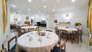 A dining area with round tables, chairs, and a buffet setup.