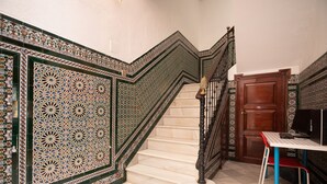 A staircase with intricate tile work, a wooden door, and a table with a chair.