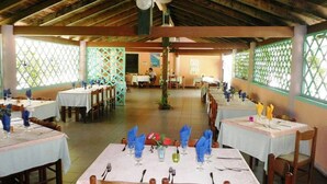 A restaurant with multiple tables set for dining, featuring white tablecloths and wooden chairs. - S'Ustiarvu (Orosei)