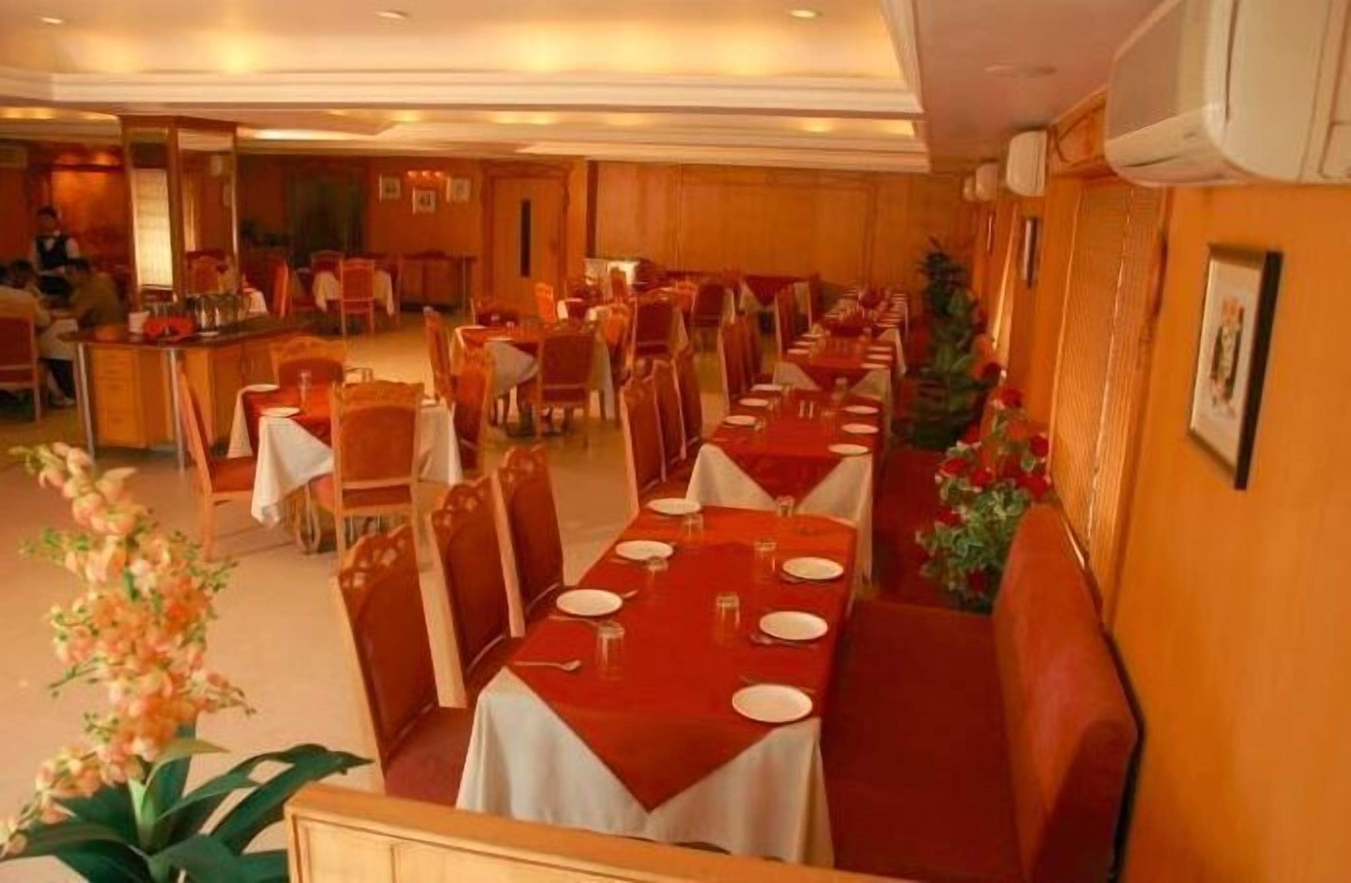 Un espace repas avec des tables dressées pour accueillir plusieurs convives, des lambris en bois sur les murs et un bar situé au fond de la pièce.