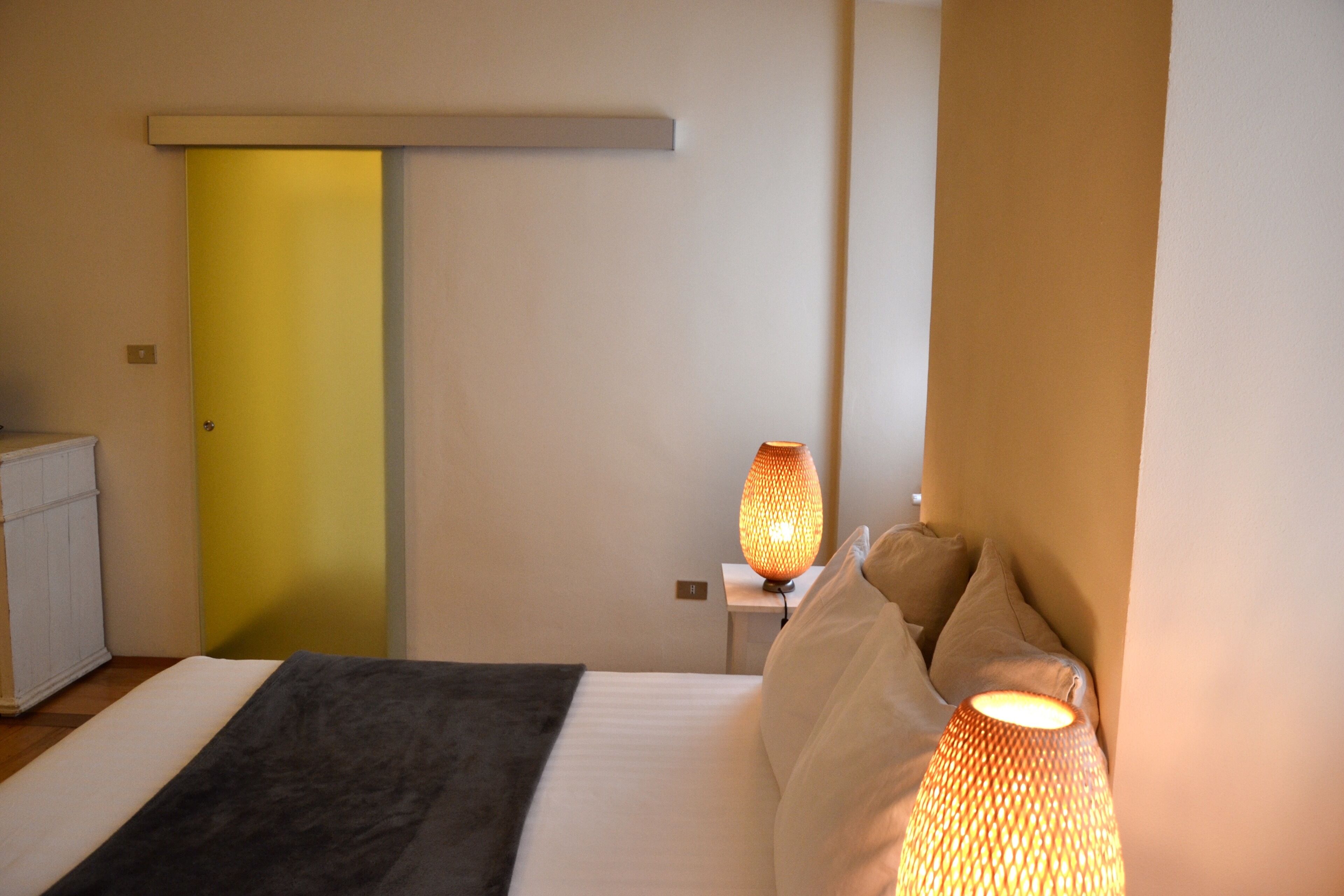 Ein Schlafzimmer mit einem Bett, einer Nachttischlampe, einem Nachttisch und einer Tür.